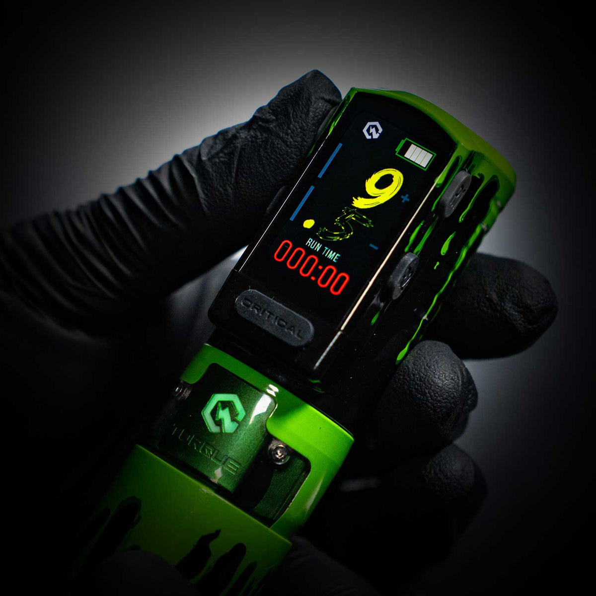 Green Critical Torque with digital display held by a gloved hand against a dark background