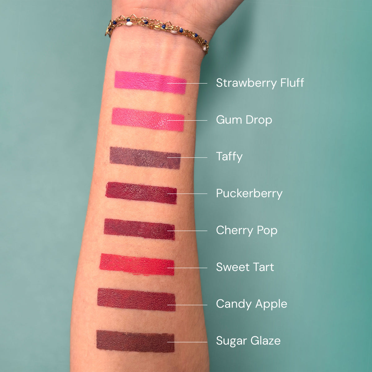 Ink swatches on a person's arm with color names labeled against a teal background