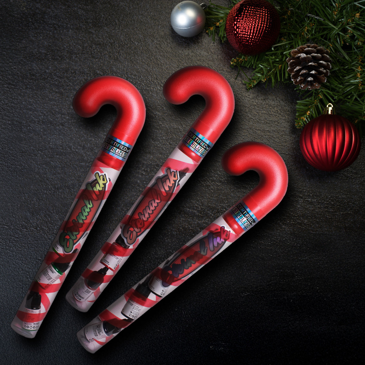 Red candy canes with Christmas-themed labels on a dark surface with festive decorations.